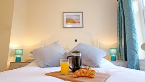 A neatly made bed with a wooden tray holding a croissant, a glass of orange juice, and a coffee pot. - 2BR Stylish Norwich Stay Near Cathedral | Parking (Norwich)