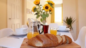 A breakfast setting with bread, a pitcher of orange juice, a coffee pot, and a vase of sunflowers. - 2BR Stylish Norwich Stay Near Cathedral | Parking (Norwich)