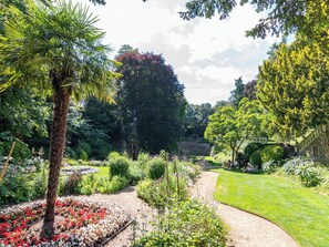 A garden with a variety of plants, a pathway, and a stone structure. - 2BR Stylish Norwich Stay Near Cathedral | Parking (Norwich)