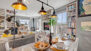 Una sala de estar acogedora con chimenea, estanterías y un comedor con una mesa dispuesta para una comida.