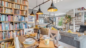 Un salón acogedor con una mesa de centro de madera dispuesta para comer, rodeado de estanterías llenas de libros.