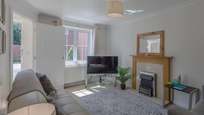 A living room with a sofa, a television, a fireplace, and a window.
