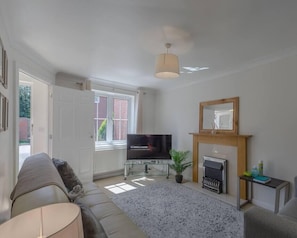 A living room with a sofa, a television, a fireplace, and a window.