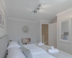 Habitación de hotel con dos camas, un espejo redondo, un mueble de madera pequeño y una lámpara en el techo.