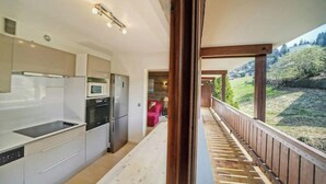 Une cuisine moderne dotée d’appareils électroménagers intégrés et offrant une vue sur un balcon donnant sur un jardin.