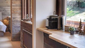 Une cuisine moderne équipée d’une machine à café, d’une bouilloire et d’une petite plante posée sur le plan de travail.