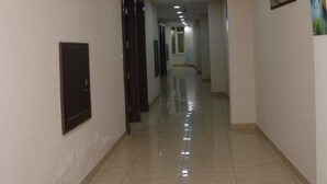A long, well-lit hallway with tiled floors and doors on both sides. - Hotel Kiran (Haridwar)