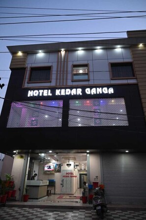 A hotel named "Hotel Kedar Ganga" with a modern facade, large windows, and a checkered pavement outside. - Hotel Kedar Ganga (Haridwar)