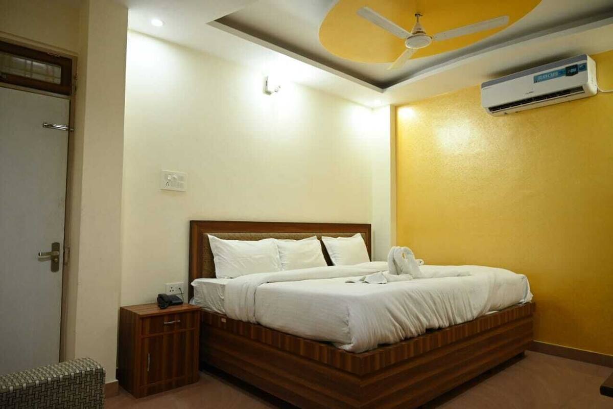 A bedroom with a wooden bed, a nightstand, a small cabinet, a ceiling fan, and an air conditioning unit.