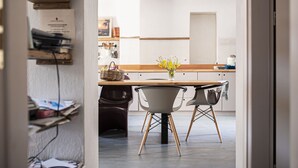 A modern kitchen with a wooden table, two chairs, and a vase of flowers. - Militiko Residence (Himarë)