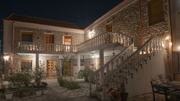 A stone building with a central courtyard, a staircase, and potted plants. - Militiko Residence (Himarë)