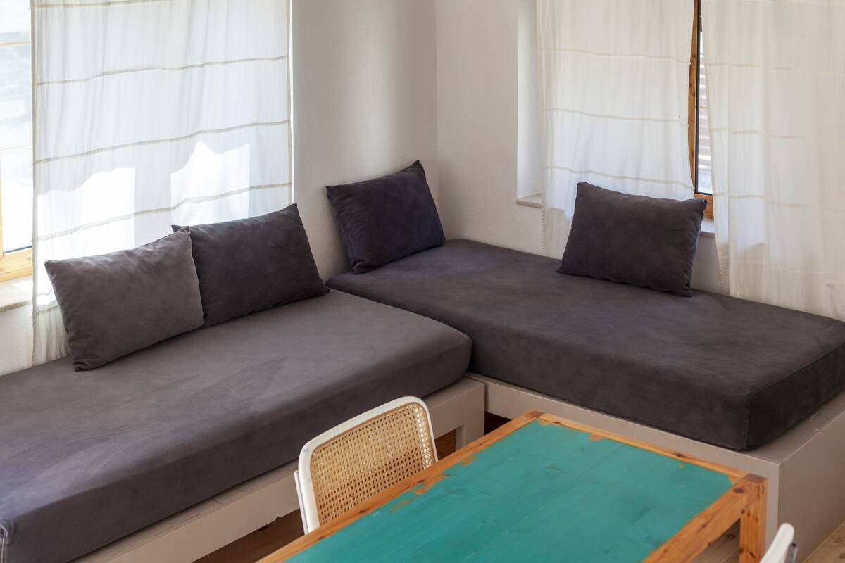 A room with two grey sofas, a small table, and a wicker chair.