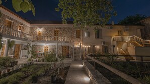 A courtyard with stone buildings, potted plants, and a central staircase. - Militiko Residence (Himarë)