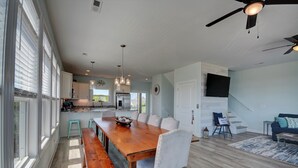 A spacious kitchen with a long wooden table, white cabinets, and pendant lighting. - Knot Salty: Ocean-view 4-bedroom for up to 11 in North Topsail Beach. (North Topsail Beach)