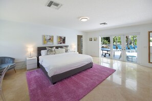 Une chambre avec un lit, une table de chevet, une chaise et une vue sur l’espace extérieur de la piscine.