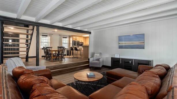 A spacious living area with a large leather sofa, a round coffee table, and a kitchen in the background. - 2Kings 2Doubles - Boat Dock in Cozy Cove PetsAsk (Mead)