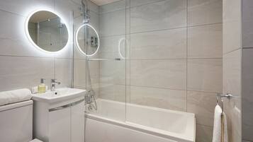 A modern bathroom with a bathtub, a sink, and two mirrors.