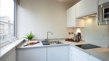Una cocina moderna con un lavamanos de acero inoxidable, una cafetera y una planta en la encimera.