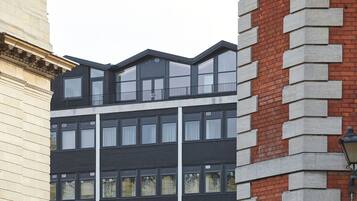 Un edificio moderno con fachada negra, ventanas amplias y una sección de ladrillo a la derecha.
