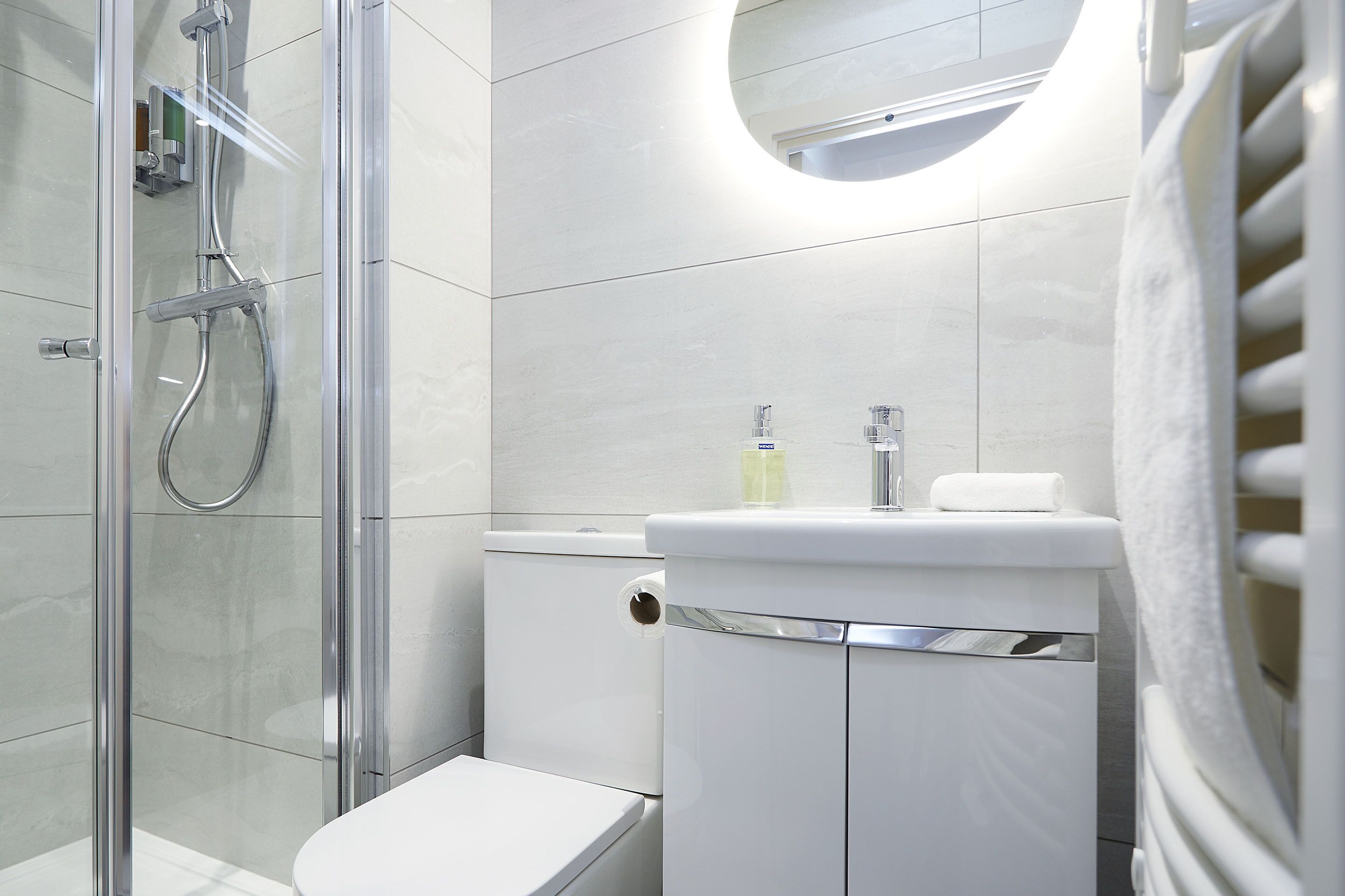 A modern bathroom with a glass-enclosed shower, a toilet, and a sink with a mirror above.