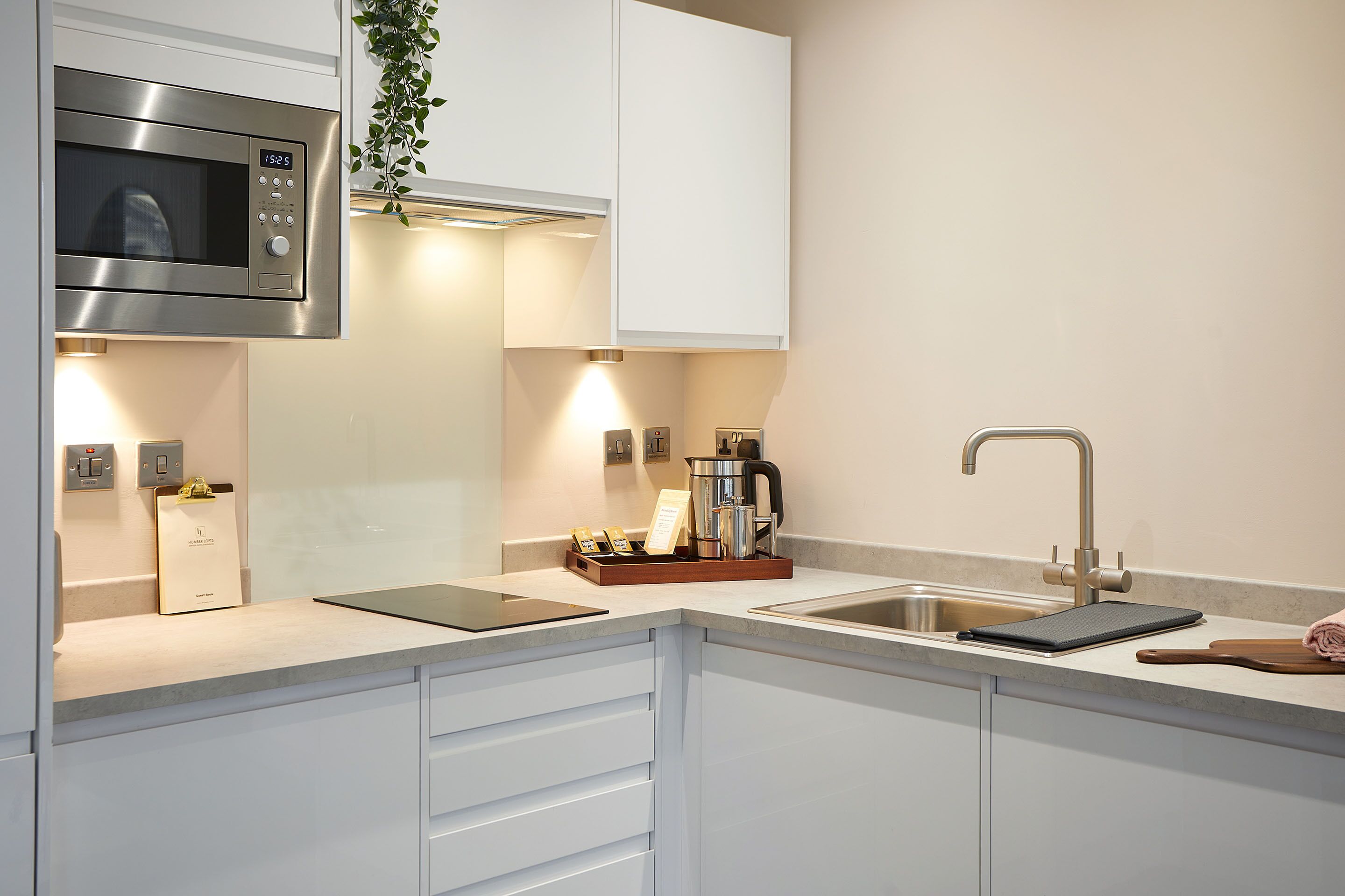 Una cocina moderna con microondas incorporado, cafetera y lavabo.