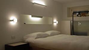Una camera da letto con un letto, un comodino, luci a parete e uno specchio.