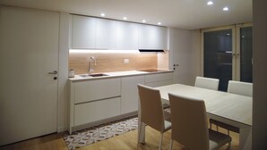 Una cucina compatta con lavandino, mobili e un'area pranzo con sedie.