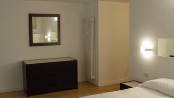 Une chambre à coucher avec un lit, une commode, un radiateur et un miroir.