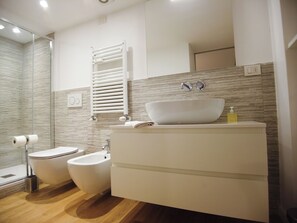 A modern bathroom with a bidet, a sink with a vessel basin, and a towel rack. - Charming loft in Moscova (Milano)