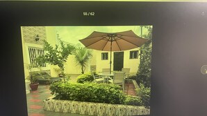 A patio area with a table and chairs, a large umbrella, and potted plants. - 4bed Villa Sleeps 8 - Wifi, Parking, Garden (Serrekunda)