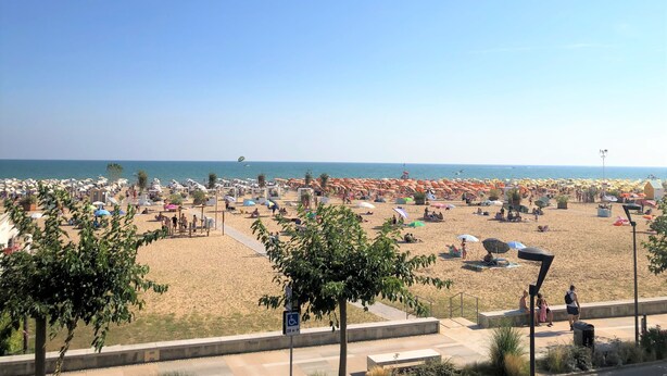 Une plage avec de nombreux parasols et beaucoup de monde.