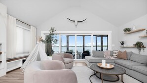 A spacious living room with a large window, a white ceiling, and a view of the water. - Roxie's Modern Lake Front House on the water! (Russells Point)