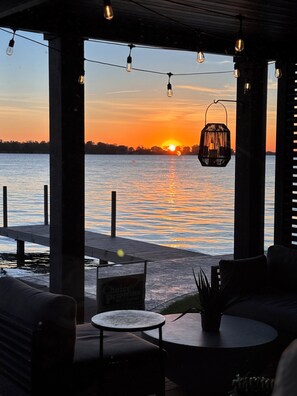 A waterfront patio with string lights, a lantern, and seating.