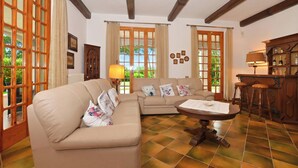 A living room with a sofa, a coffee table, and a bar area with stools. - Villa Cerbaie (Fucecchio)