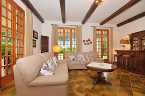 A living room with a sofa, a coffee table, and a bar area with stools. - Villa Cerbaie (Fucecchio)