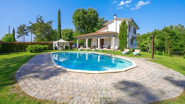 A swimming pool with a paved deck, a covered seating area, and a house with a tiled roof. - Villa Cerbaie (Fucecchio)