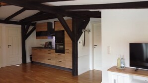 A modern kitchen with wooden cabinets and a built-in oven. There is a wooden floor and a white door in the background. - House (Klein Upahl)