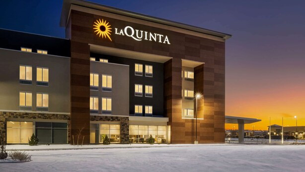 Un hotel con un llamativo letrero de 'LaQuinta', varias ventanas y un estacionamiento.