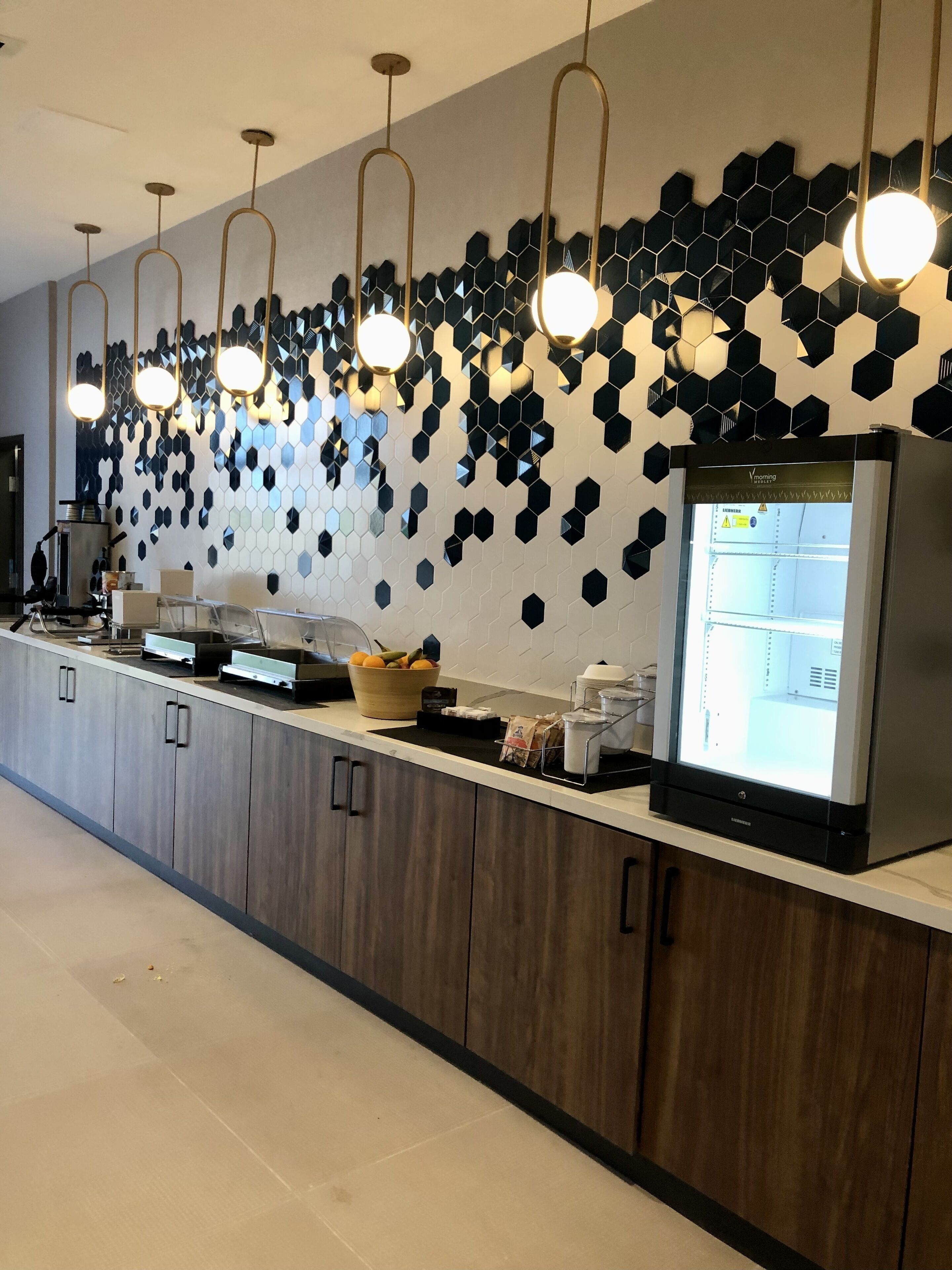 Una cocina moderna con una encimera larga, un refrigerador y un microondas.