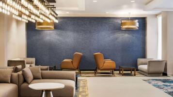 A modern lobby with a sectional sofa, two armchairs, a round table, and a large blue accent wall.