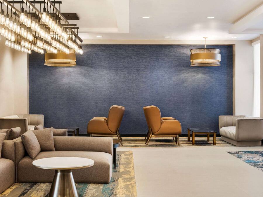 A modern lobby with a sectional sofa, two armchairs, a round table, and a large blue accent wall.