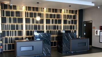 A reception area with two marble reception desks, a modern wall design with vertical lines, and ceiling-mounted lighting.
