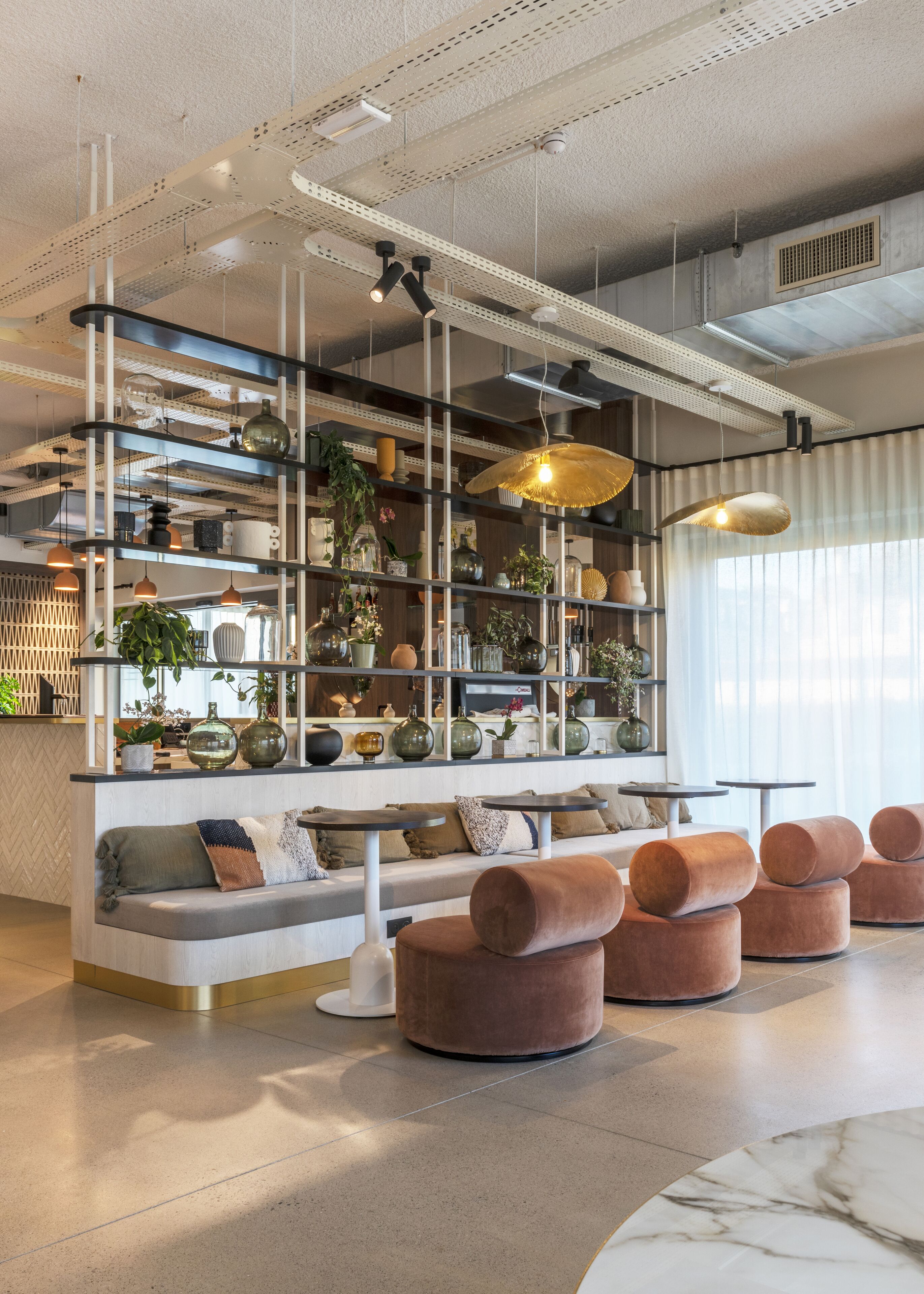 Un interior moderno con una zona de estar, estanterías con objetos decorativos e iluminación colgante.
