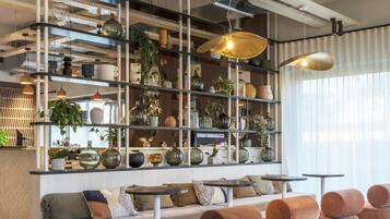 Un interior moderno con una zona de estar, estanterías con objetos decorativos e iluminación colgante.