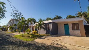 A residential building with a blue door, surrounded by palm trees and a clear sky. - Private Pool, Modern 2 bedroom Villa (Juan Dolio)