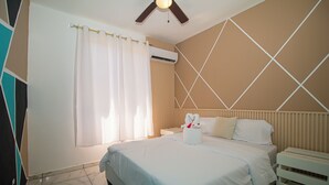 A hotel room with a bed, a nightstand, a ceiling fan, and a window with curtains. - Private Pool, Modern 2 bedroom Villa (Juan Dolio)