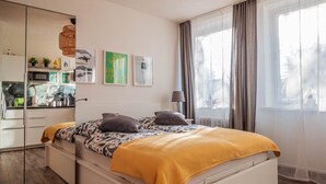 Un dormitorio moderno con cama, mesita de noche y un espejo grande.