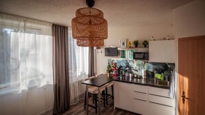 Una cocina moderna con armarios blancos, encimera negra y lámpara de ratán colgante.