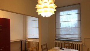 Un comedor con una mesa, sillas, un radiador y una ventana con persianas.