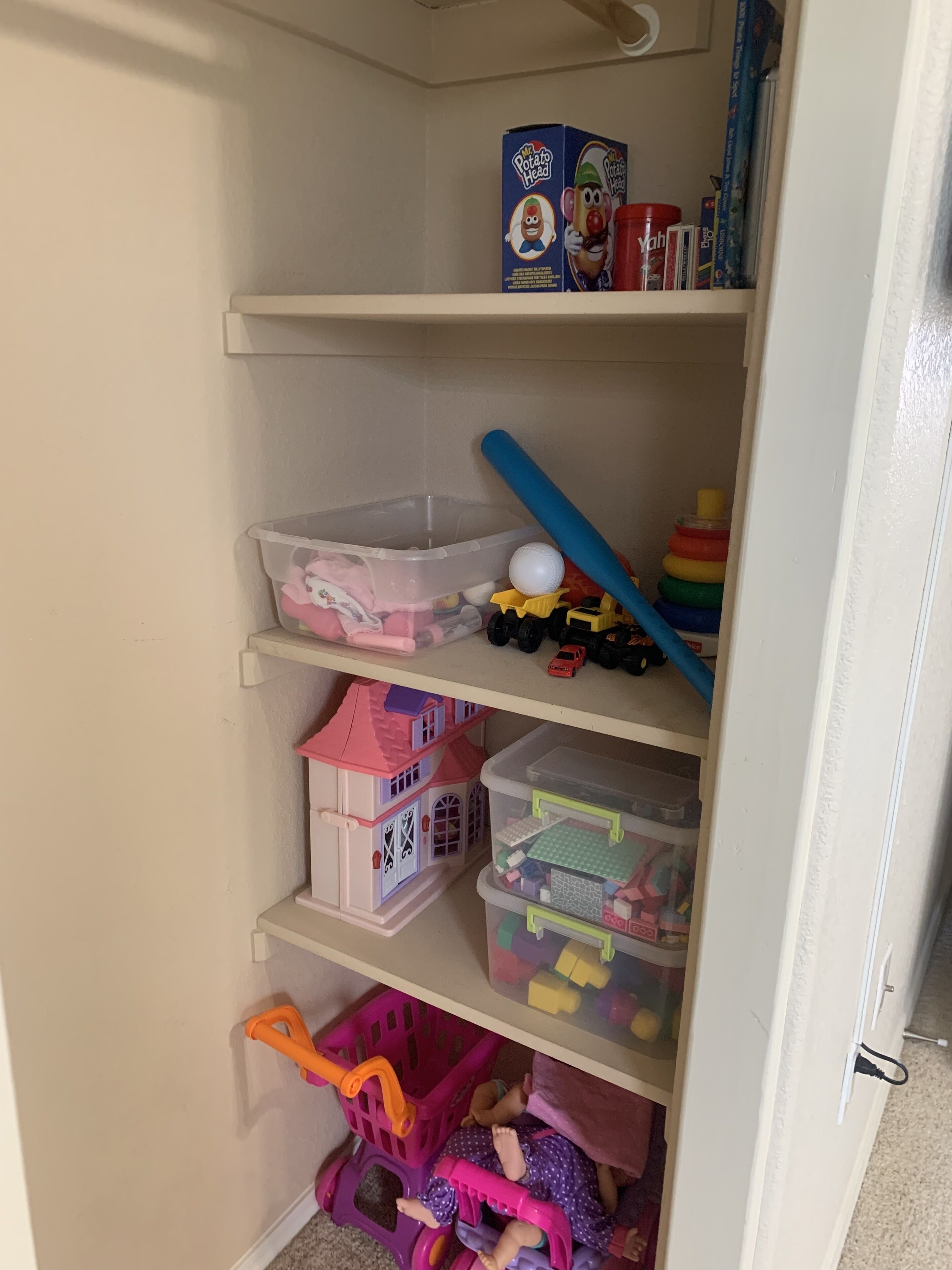A storage area with shelves containing toys, a plastic container, and a toy car.